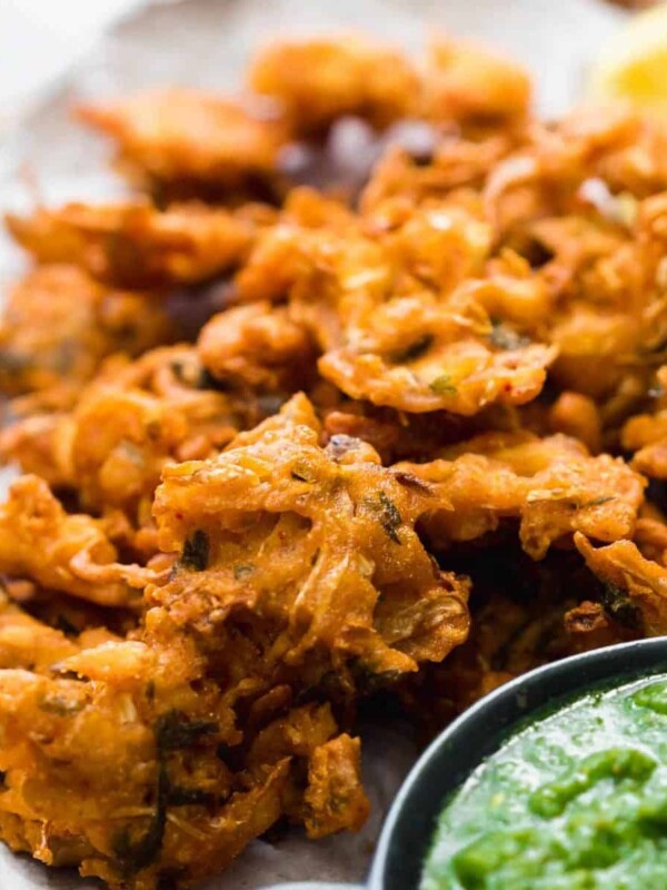 Crunchy vegetable pakoras served on a wooden board with green coriander chutney