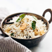 Coconut rice served in a kadhai topped with roasted cashews and curry leaves