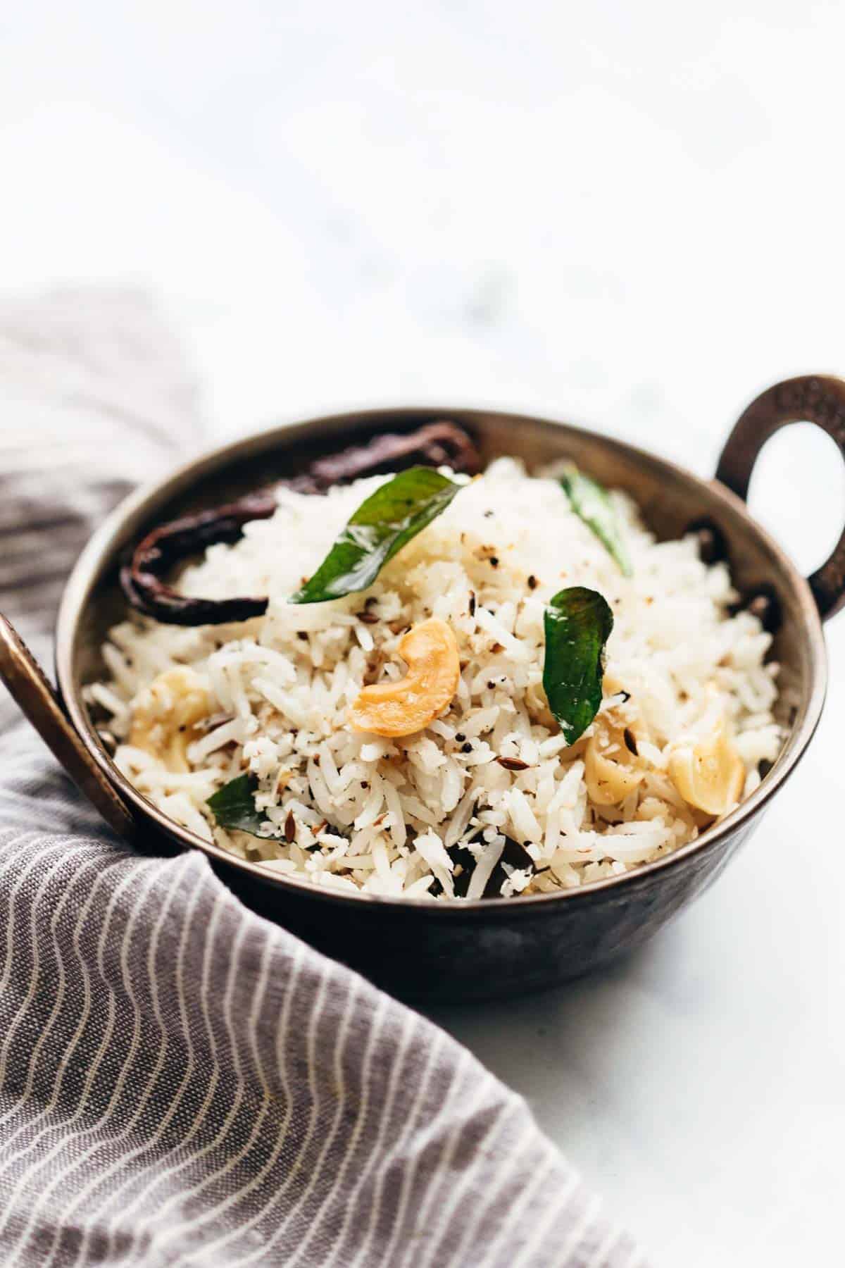 Coconut rice served in a kadhai topped with roasted cashews and curry leaves