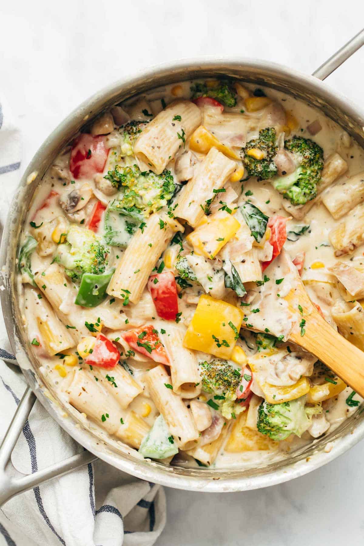 White sauce pasta with vegetables directly from the stovetop in a pan.