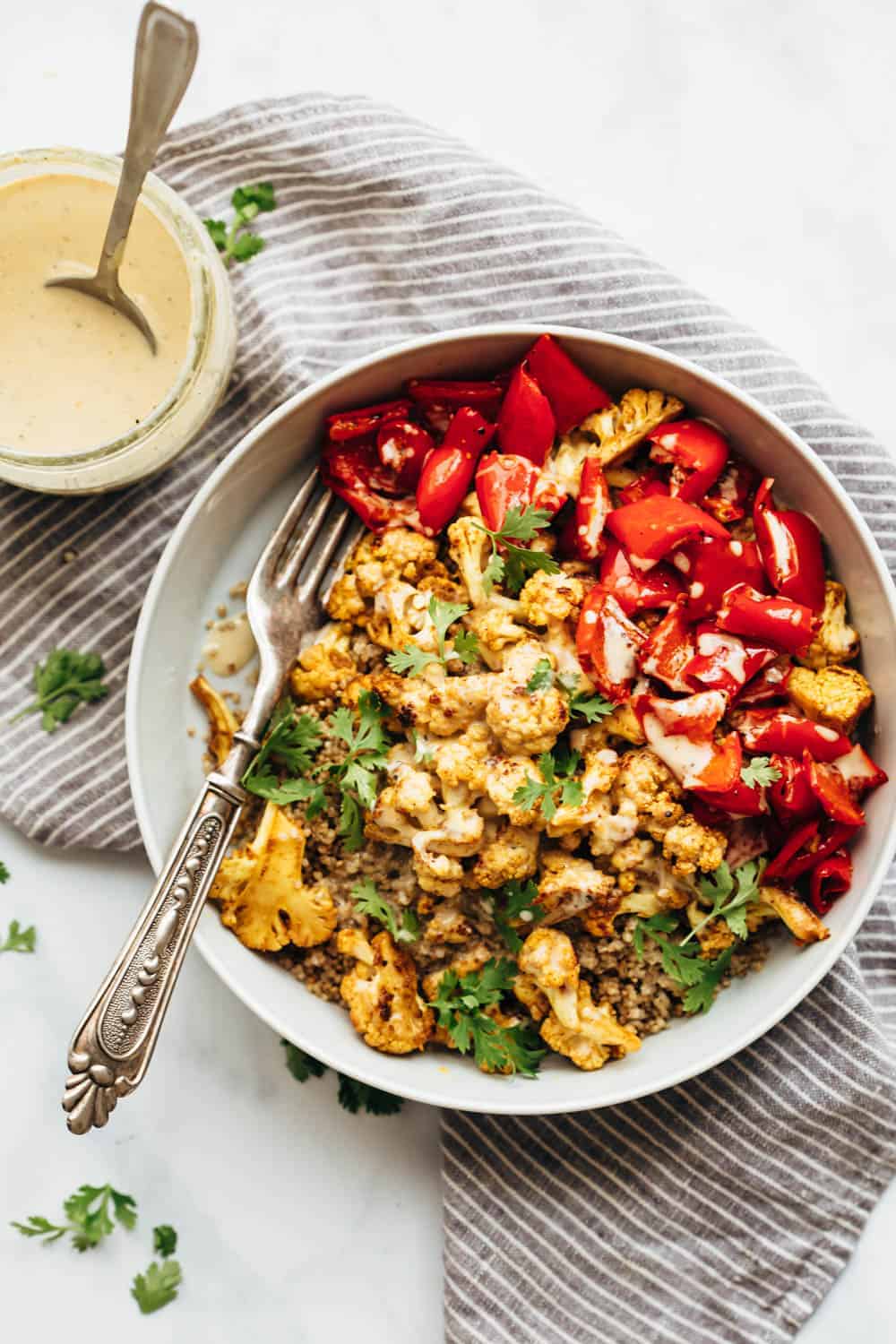 Curried roasted cauliflower bowl with tahini dressing drizzled on top