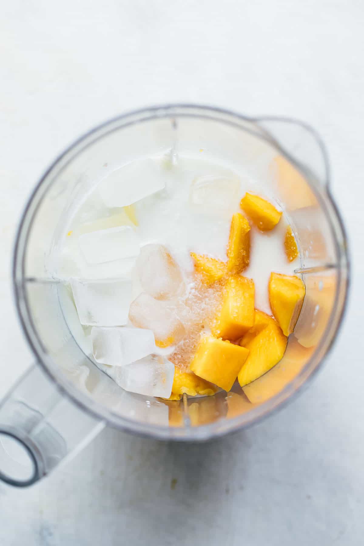 All the ingredients for creamy mango lassi in a blender