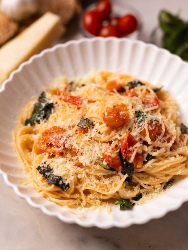 tomato basil pasta garnished with lots of cheese and served in a white pasta plate