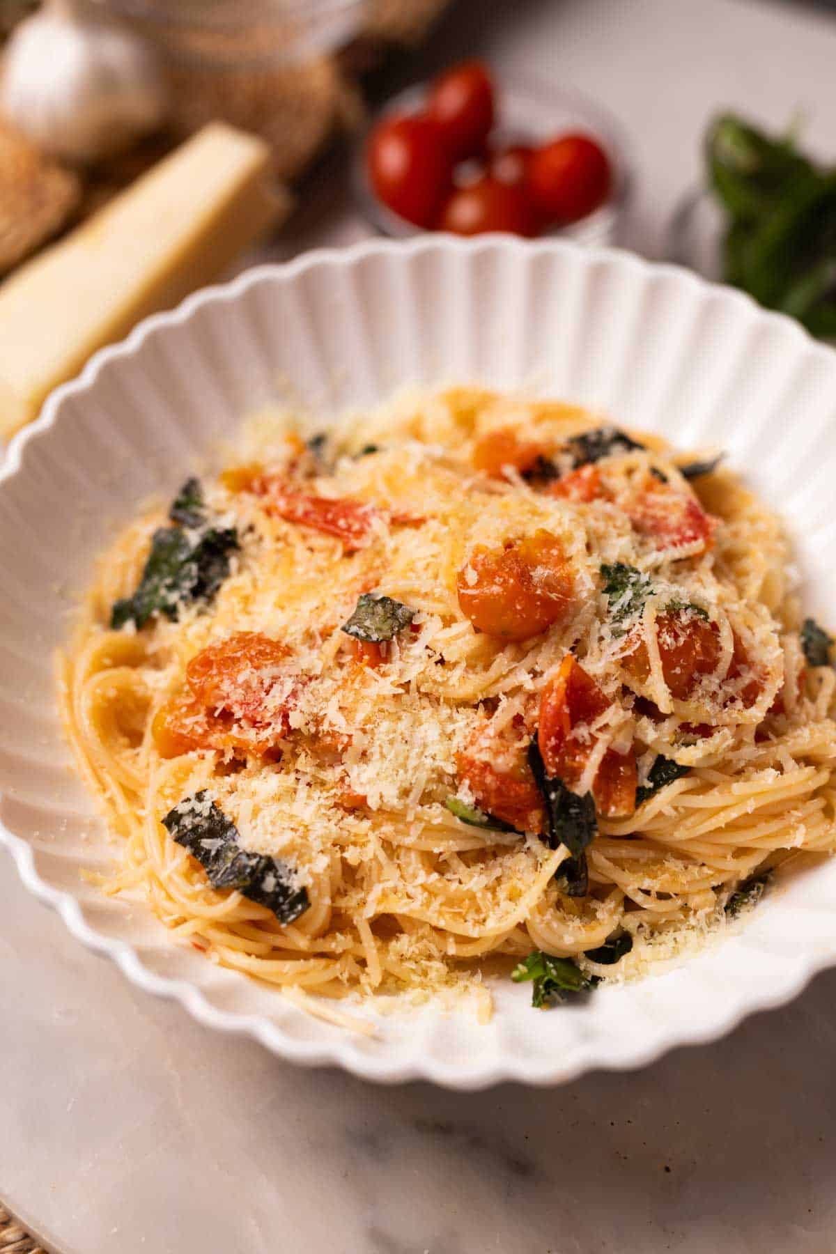 tomato basil pasta garnished with lots of cheese and served in a white pasta plate