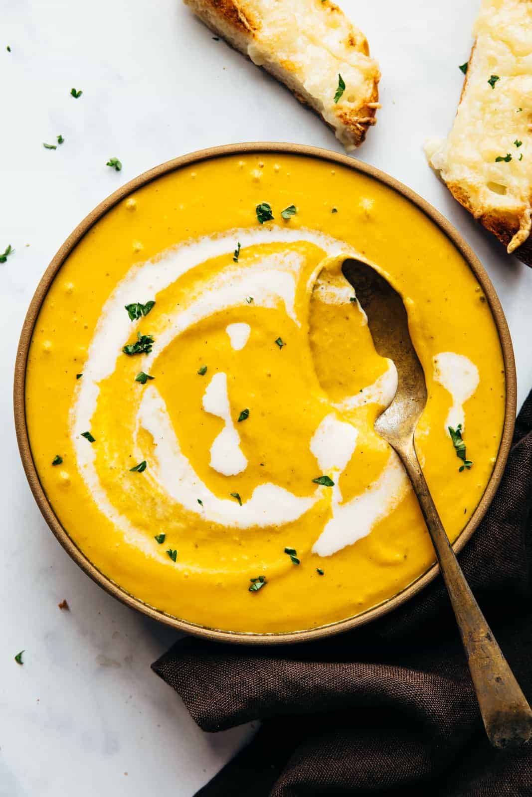 Creamy roasted pumpkin soup in a bowl with cheesy bread