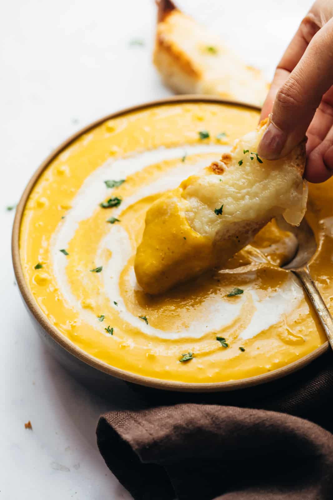 Dunking cheesy bread in pumpkin soup