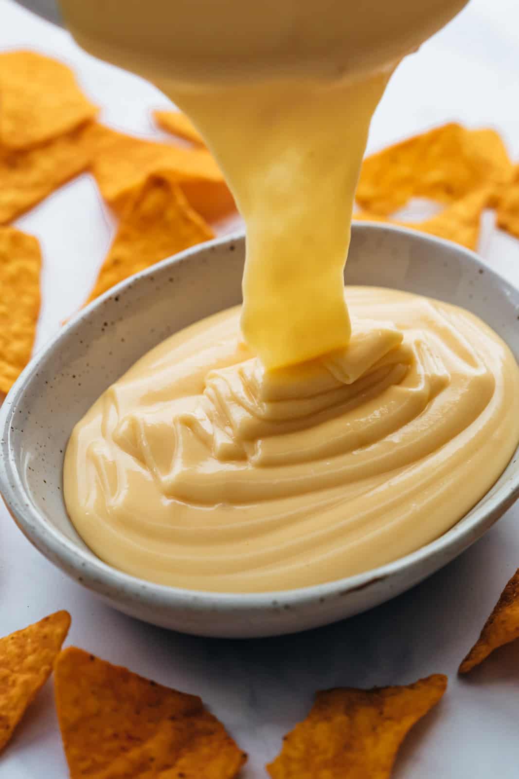 Pouring nacho cheese sauce into a serving dip bowl