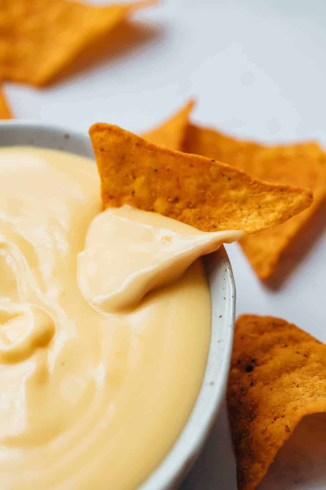 Nacho dipped in spicy nacho cheese sauce