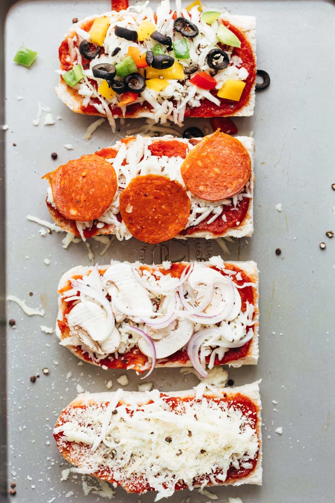 Toppings on french bread pizza toasts about to go into the oven
