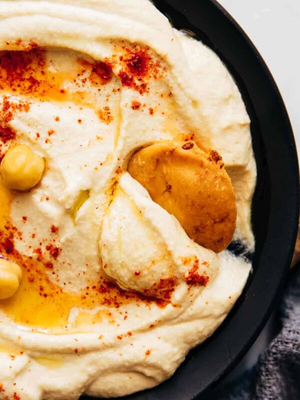 Closeup of pita scooping up hummus to show smooth texture