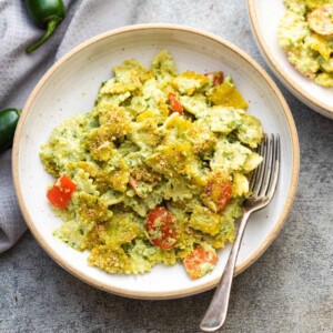 pasta in jalapeno pesto served in a white pasta bowl with a fork