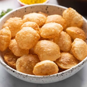 Puris served in a bowl with the pani and filling in the background
