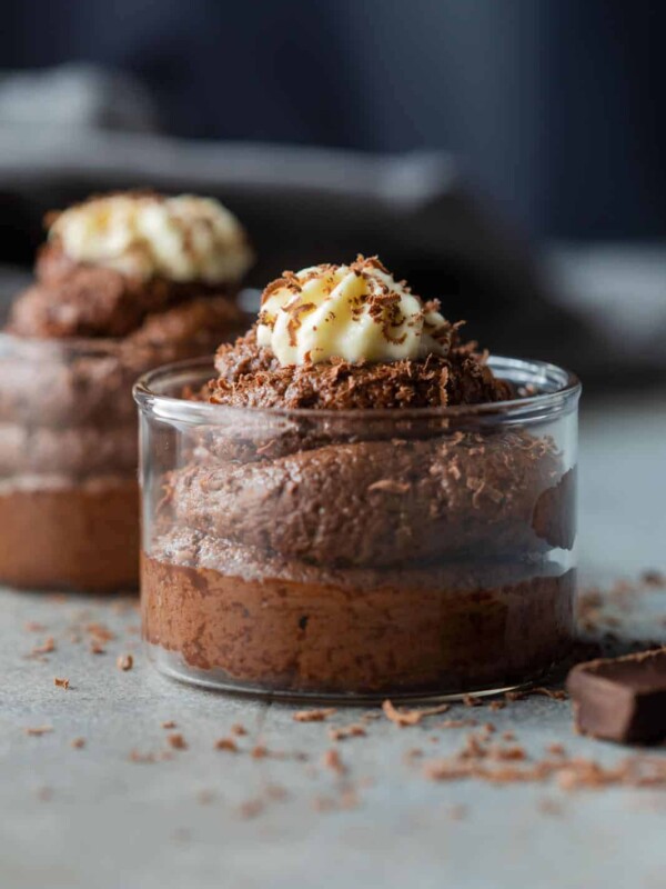 eggless chocolate mousse served in glass jars topped with whipped cream and a sprinkle of grated chocolate