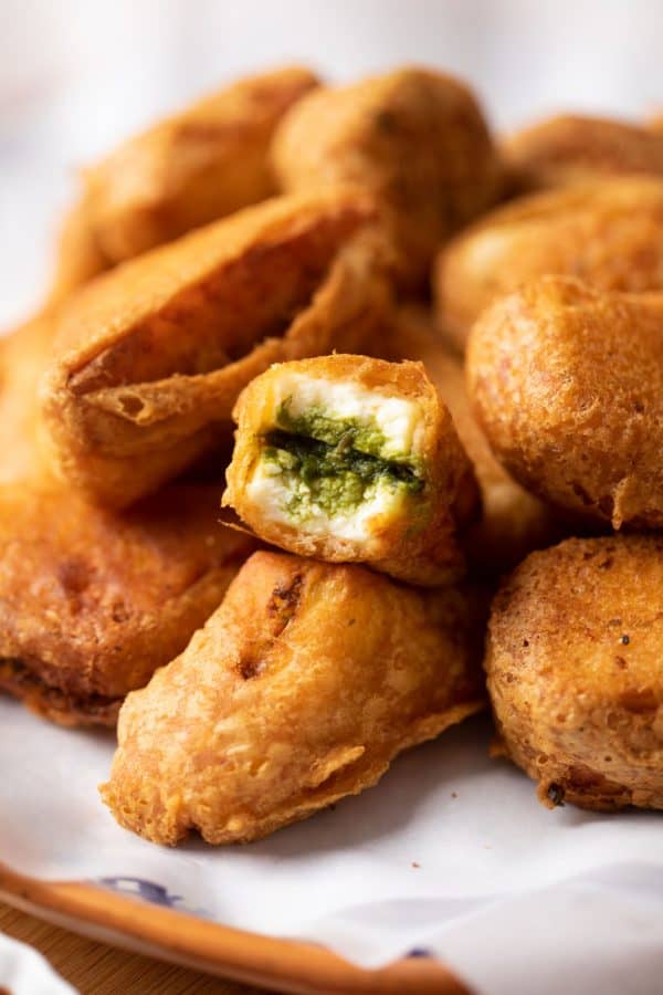 Chutney sandwich paneer pakora bite on a stack of paneer pakoras