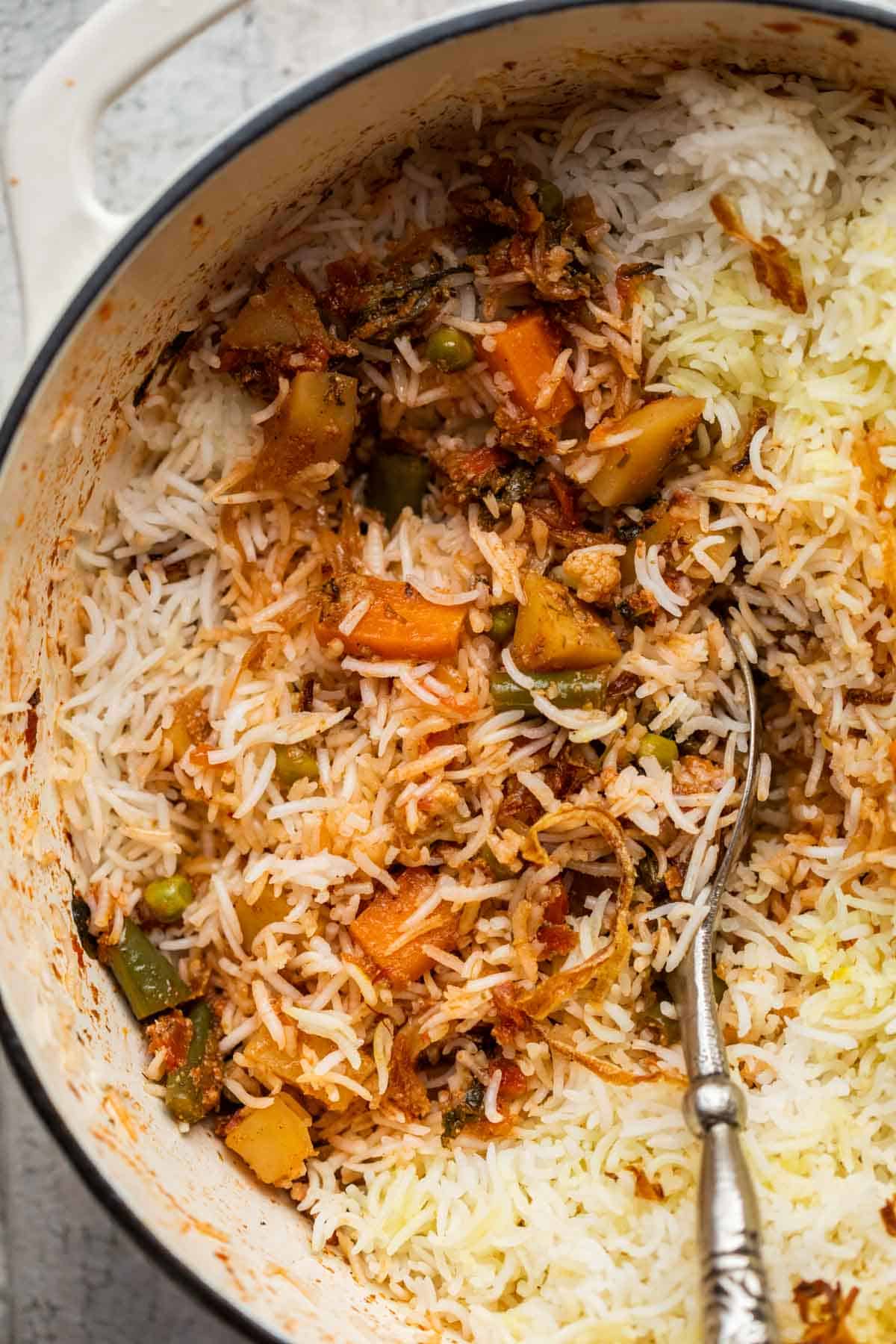 Closeup of veg biryani in the pot after a few spoonfuls have been served