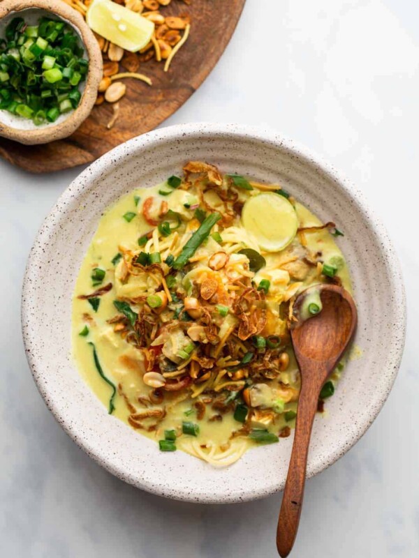 Burmese Khow Suey served in a white bowl with all the toppings and noodles