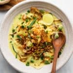 Burmese Khow Suey served in a white bowl with all the toppings and noodles