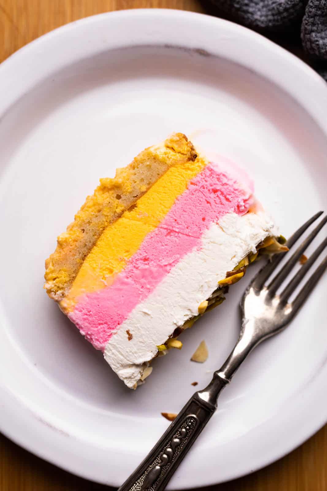 A slice of classic cassata with cheesecake on a plate with a fork
