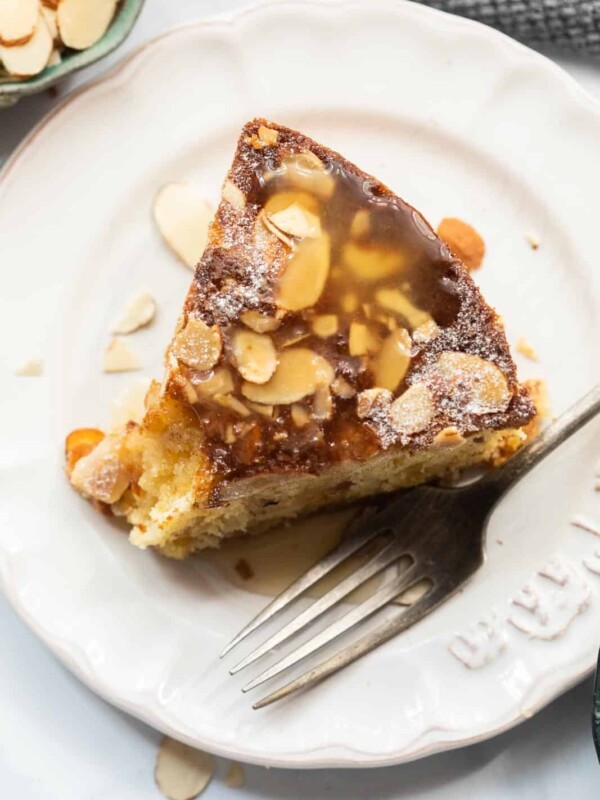 A slice of Dundee Cake kept on a white plate with a fork