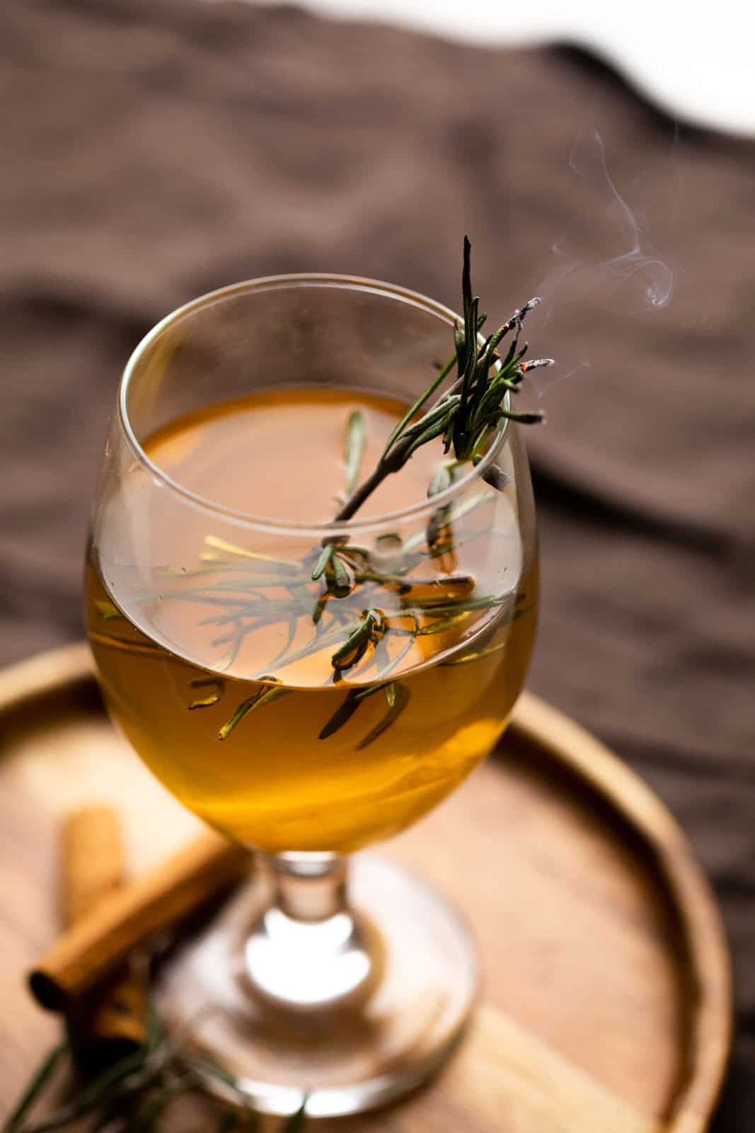 spiced hot toddy served garnished with thyme and served in a wine glass