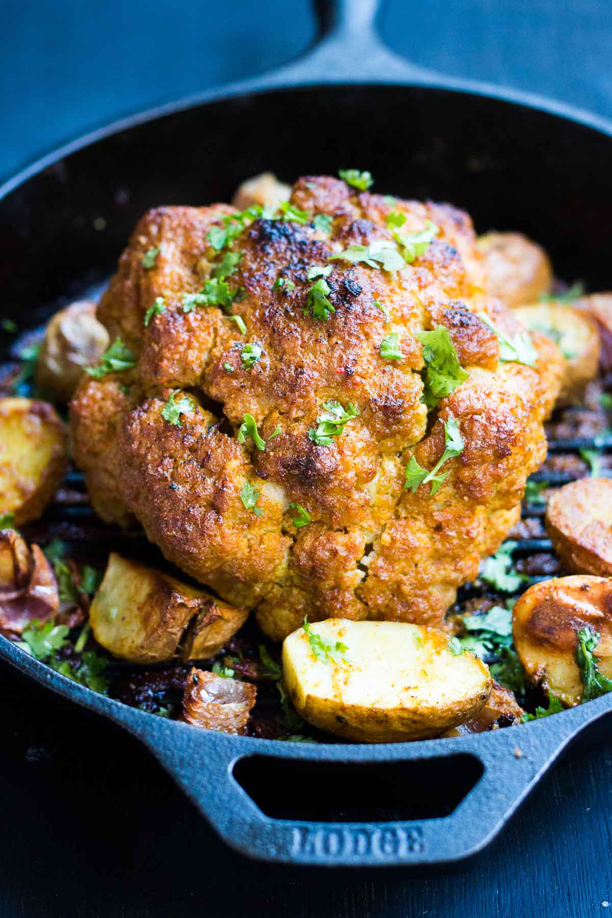 The tandoori cauliflower served with onions and potatoes in a skillet.
