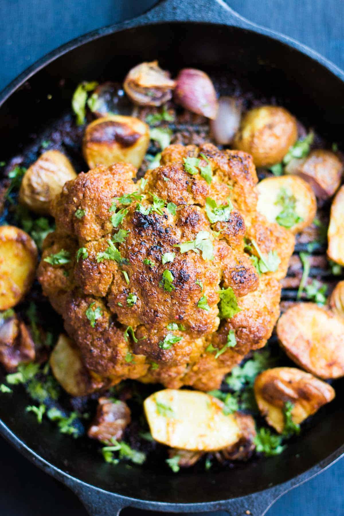 The tandoori cauliflower served with onions and potatoes in a skillet.