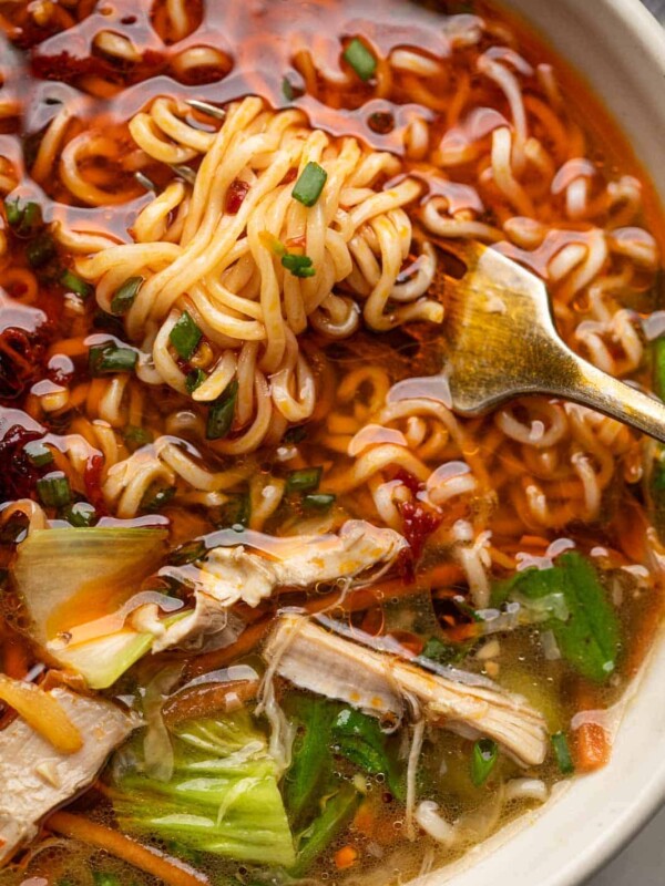 Closeup of noodles twirled around a fork in a bowl of chicken thukpa soup