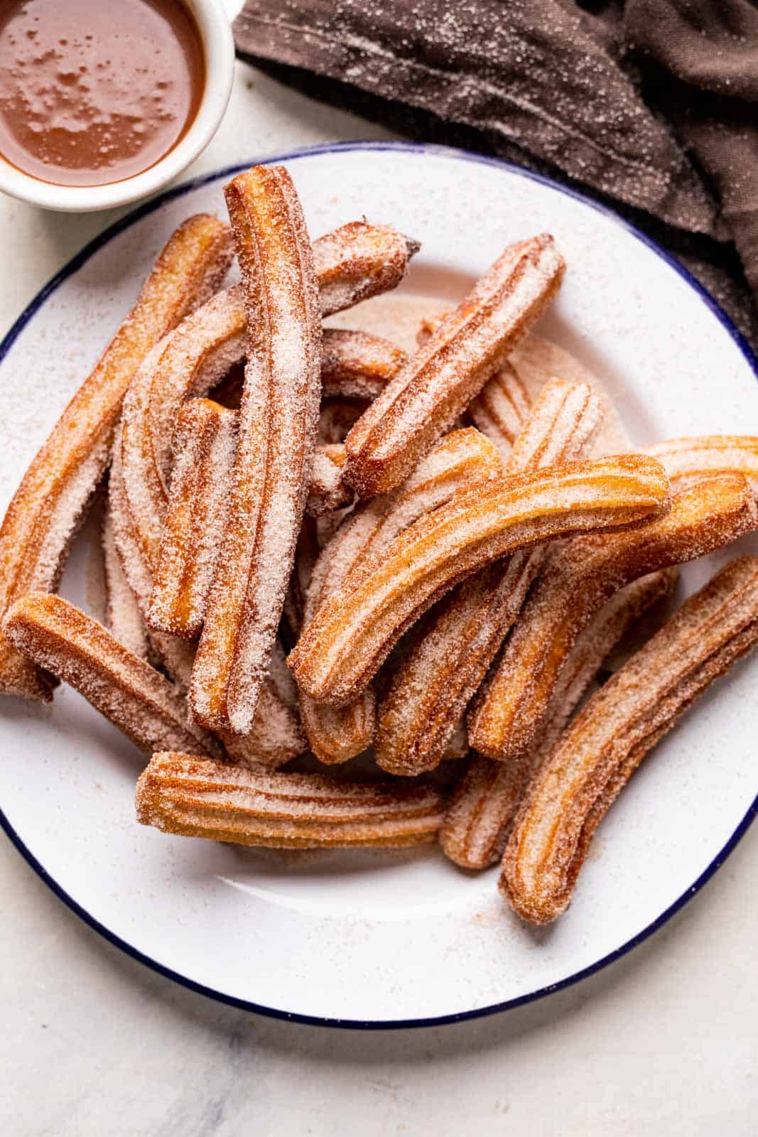 Churros piled on a plate and served with chocolate sauce