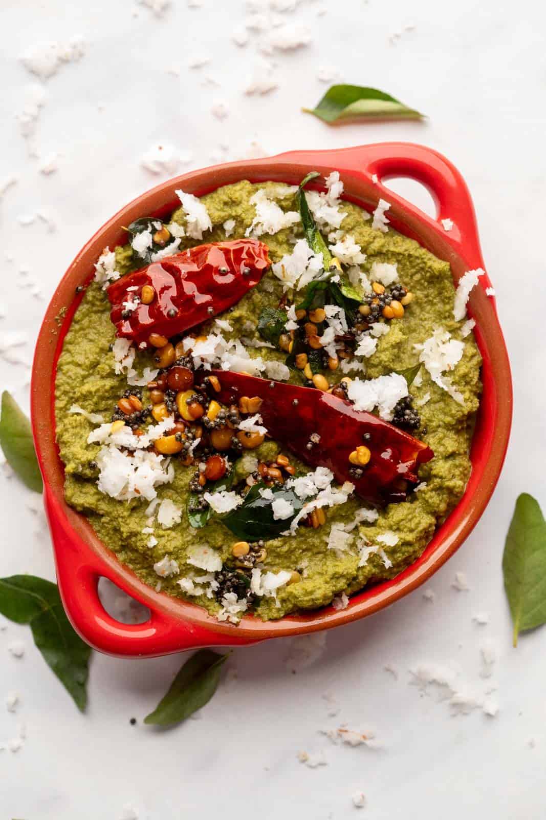 Coconut Coriander Chutney served in a red bowl with tempering on top