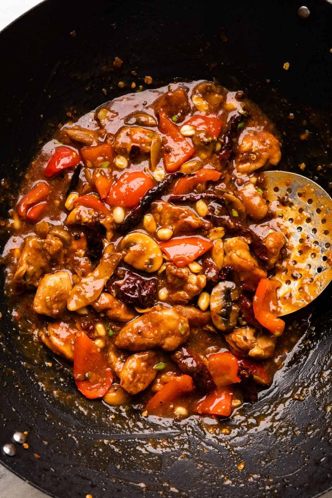 Kung Pao chicken pictures in the wok that it was cooked in with a skimmer