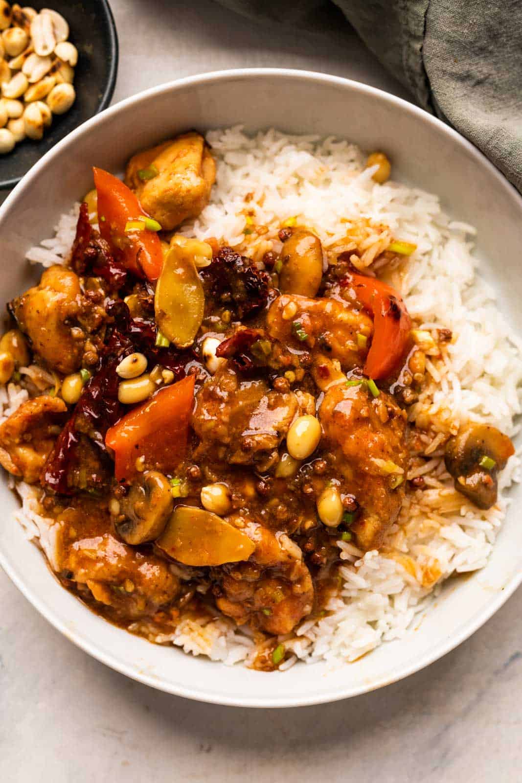 Kung Pao Chicken served over rice in a bowl with peanuts on the side