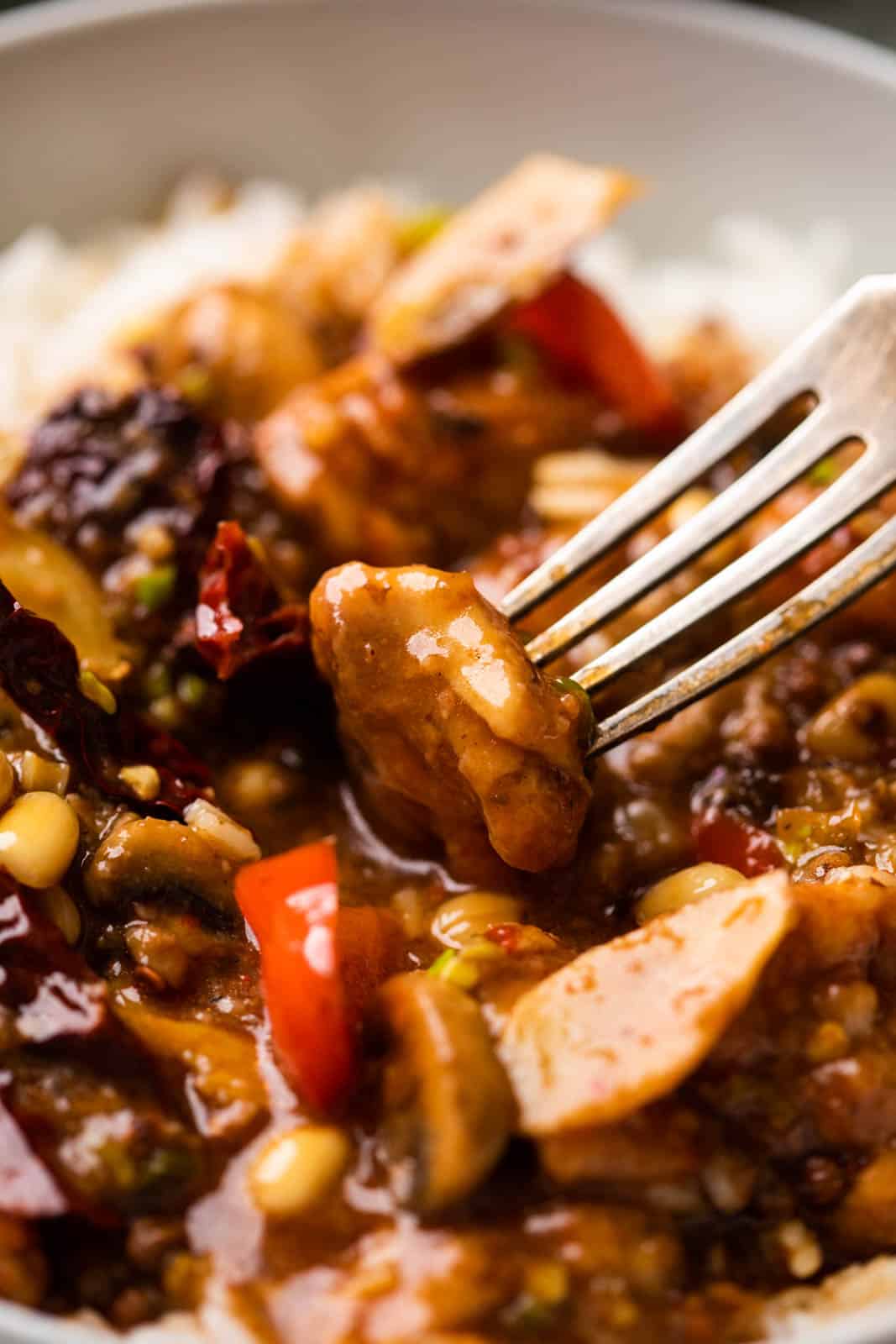 Closeup of a piece of kung pao chicken on a fork