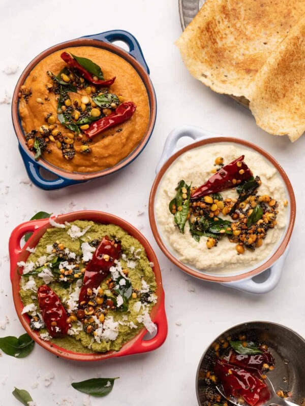 3 south indian chutneys served in bowls with two dosas on the side