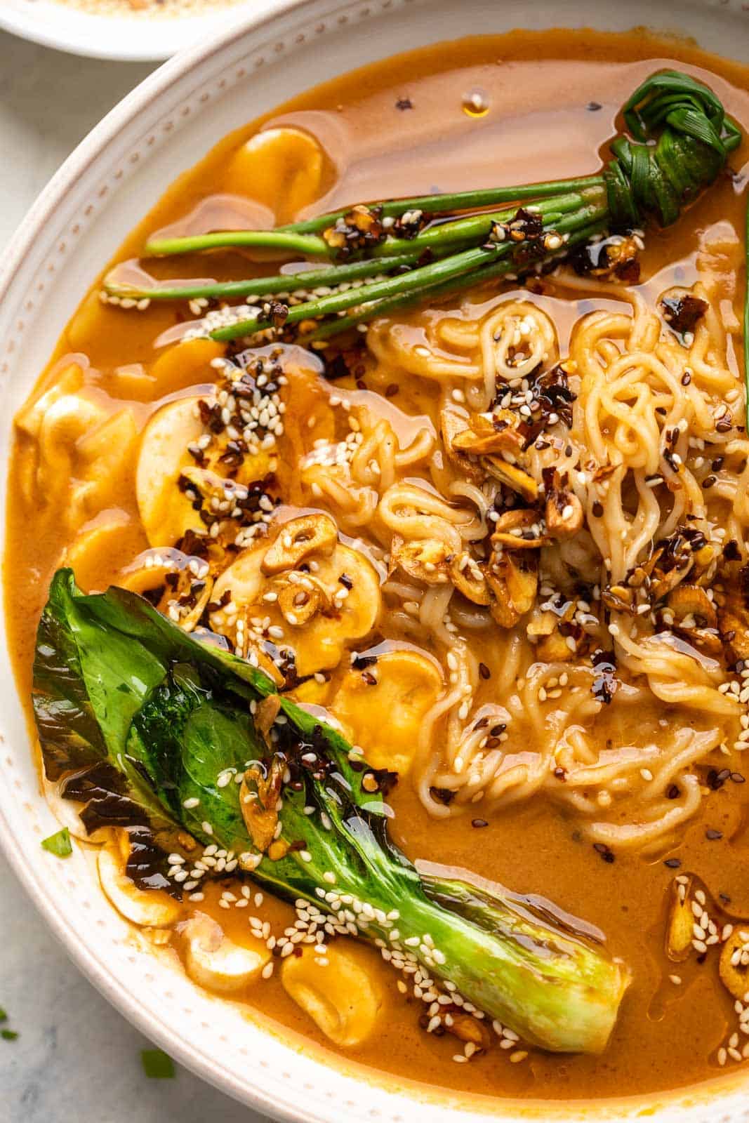 Closeup of the veg ramen served in a white bowl showing the fried garlic and noodles up close