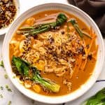 A bowl of vegetarian ramen topped with chives and bok choy and served with sesame chilli oil on the side