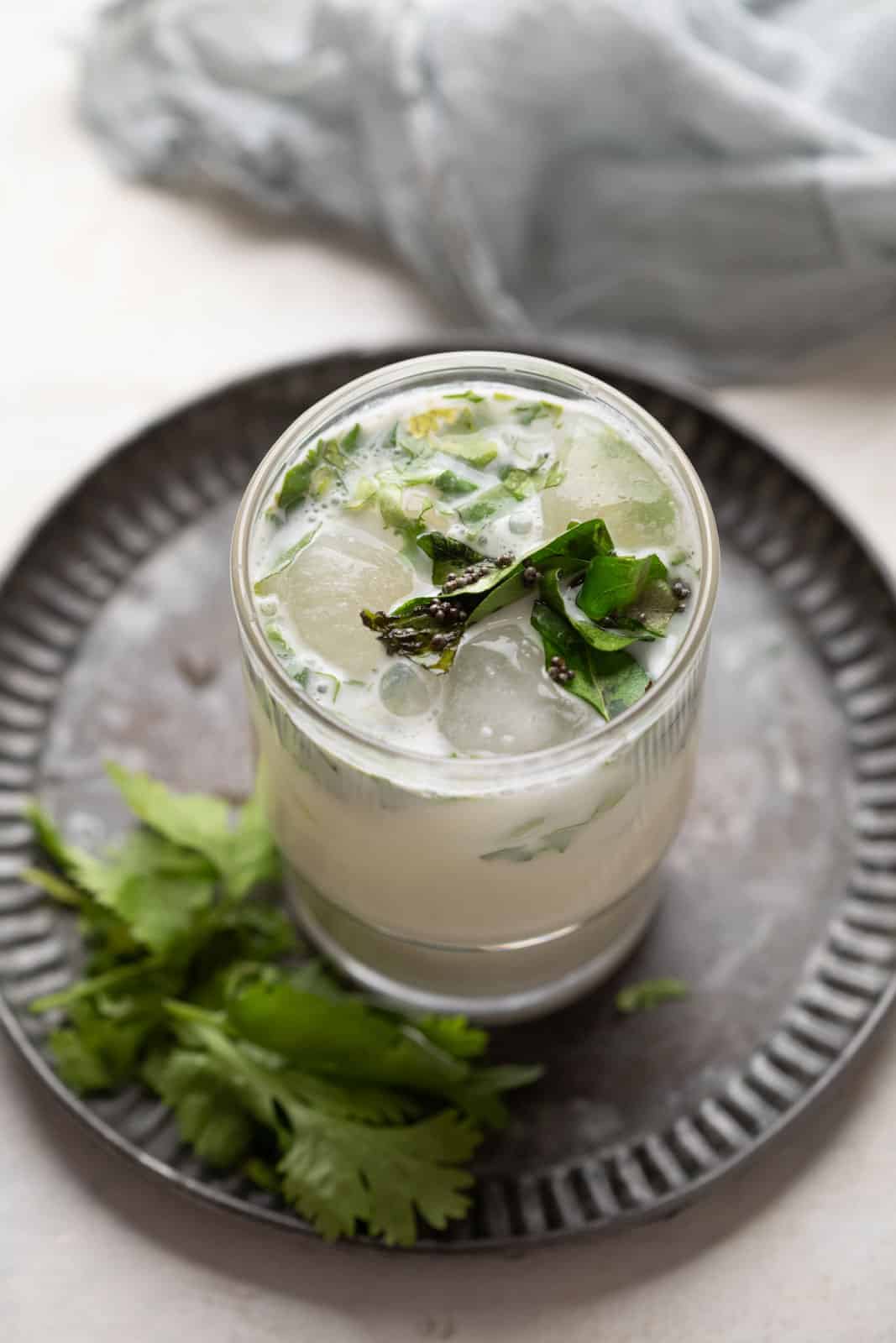 masala chaas with ice cubes served in a glass on a metal tray