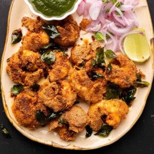 Prawn Rava Fry served on a beige platter with chutney and sliced onions on the side