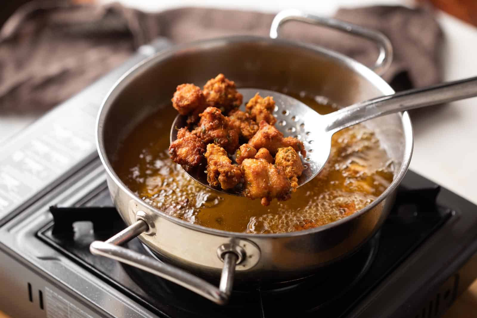 Chicken 65 deep fried in oil just being taken out of a kadhai