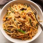 Chicken Chow mein served in a white bowl with a fork on the side
