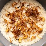 Ghee Rice pictured in the pot that it was made in topped with fried onions and fried cashews