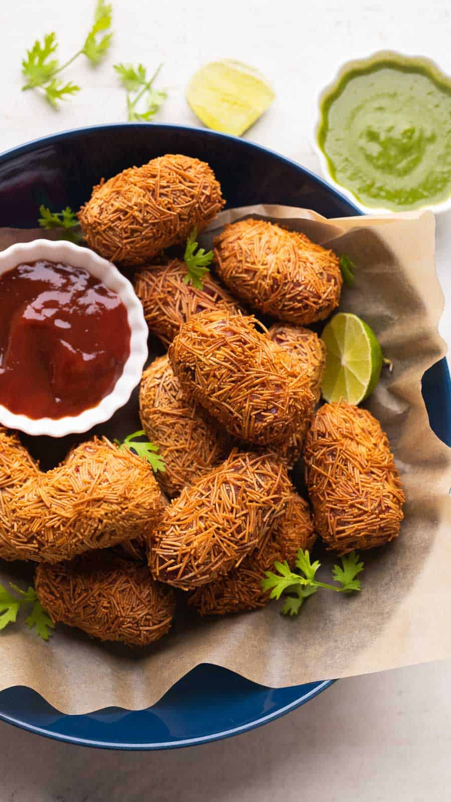Veg Cutlets served in a blue bowl with green chutney and ketchup