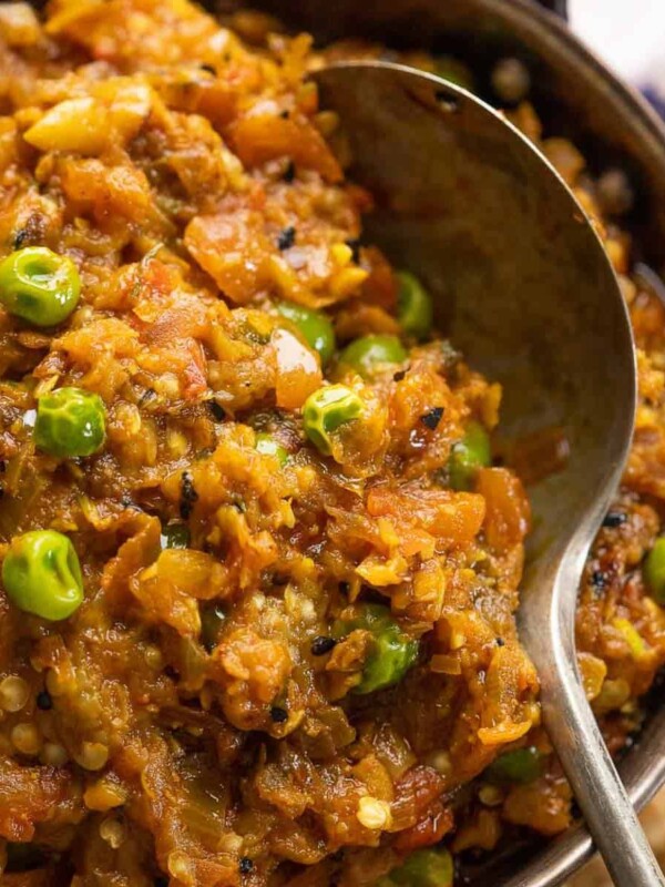 Baingan Bharta served in a copped kadhai with tandoori roti and sliced onions on the side