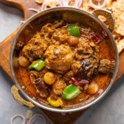 Kadai Chicken served in a copper kadai with tandoori roti and onions on the side