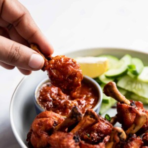 Chicken lollipop being dipped in schezwan sauce