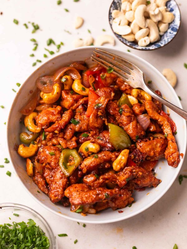 dragon chicken served in a white bowl with a fork and accompaniments