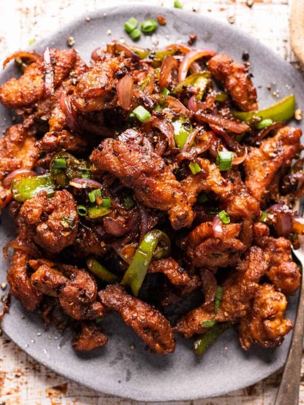 Salt and pepper chicken served on a grey plate with a fork
