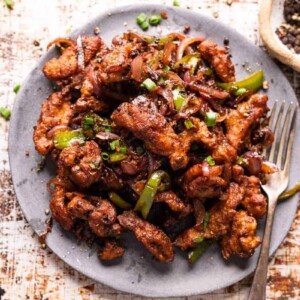 Salt and pepper chicken served on a grey plate with a fork