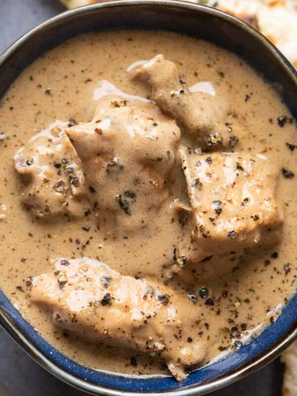 Chicken kali mirch gravy served in a blue bowl with naan on the side