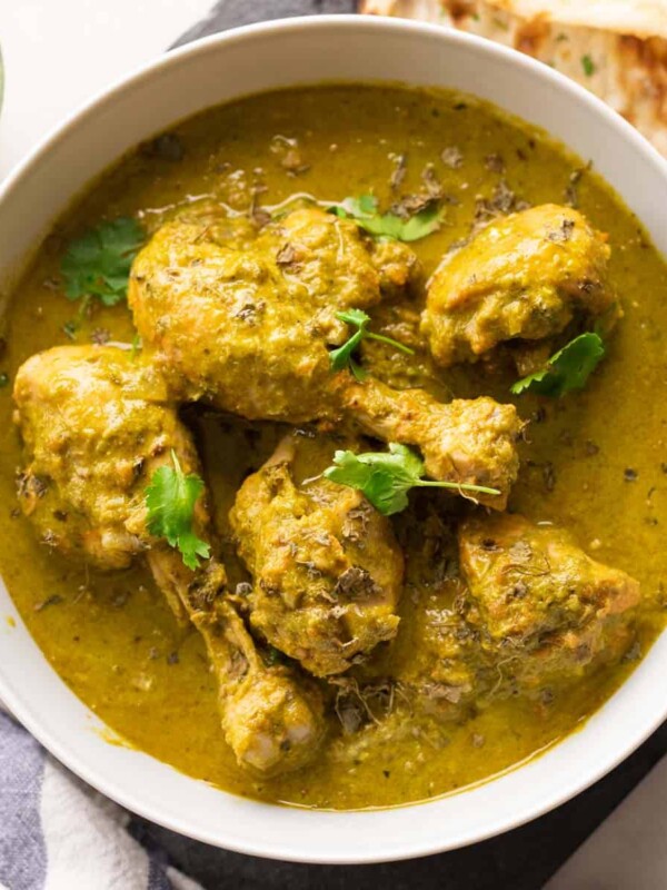 Picture of saag chicken served in a white bowl with naan on the side