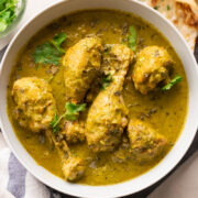 Picture of saag chicken served in a white bowl with naan on the side